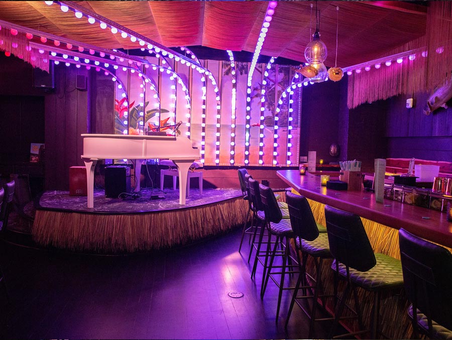 NYC Bar and piano with neon strip lights in the background at a Tiki Bar in New York City.